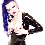 First pic of Alt model Darenzia in long black latex dress and platform shoes poses with big gun