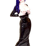 Third pic of Alt model Darenzia in long black latex dress and platform shoes poses with big gun
