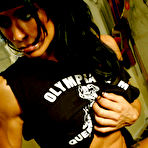 Fourth pic of Dark haired bodybuilder Tara Scotti in black uniform shows off her muscle torso