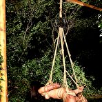 Fourth pic of Marica Hase naked and chained in the yard bound and forced onto her knees during bondage.