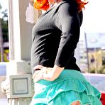 Third pic of Redhead Dani Jensen in green mini skirt and high black boots flashes her ass in public