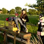 Second pic of Bimba Sawacco in mask and latex suit gets dominated by Susi M and Lady K outdoors