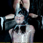 First pic of SexPreviews - Kiki Cali is wrapped in plastic with arms bound in leather armbinder on the floor in dungeon