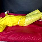 Fourth pic of Shinynylonartsbound | Watching sexy Pia being tied and gagged with ropes on a bed and a clothgag wearing sexy yellow shiny nylon rainwear (Video)