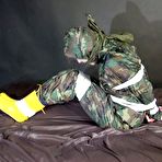 Second pic of Shinynylonartsbound | Watching sexy Pia being tied and gagged with tape on a bed wearing a sexy camouflage shiny nylon rainpants and a rainjacket as well as yellow rubber boots (Video)