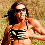 Second pic of Bodybuilder Lynnie Brooks poses on sandy ground in a bikini and sunglasses