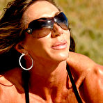 Fourth pic of Bodybuilder Lynnie Brooks poses on sandy ground in a bikini and sunglasses