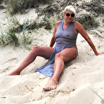 Second pic of Beautiful busty mature Dimonty poses fully clothed in sheer dress at the beach