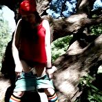 Third pic of Young blonde Larisa takes a pee behind a tree in multi-coloured knee socks