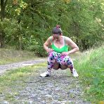 Third pic of European female Valentina Ross squats for a pee while strolling a country road