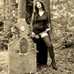 Second pic of Goth girl Barby Slut bares her big tits and twat atop a casket in the woods