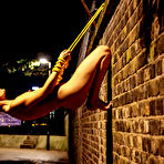 Second pic of Naked teen is restrained to a brick wall with yellow rope at night