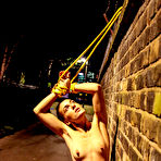Third pic of Naked teen is restrained to a brick wall with yellow rope at night