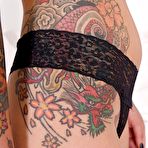Second pic of Heavily tattooed alt model Lauren revealing pierced cunt while posing naked