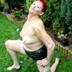 Second pic of Redhead granny Valgasmic Exposed poses nude in a yard with nylons on